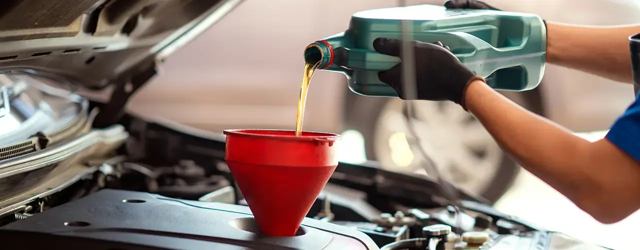 A person pouring engine oil into a car engine.