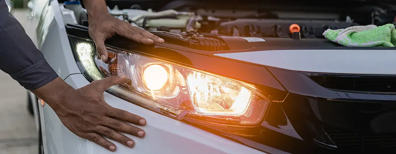 A man inspects the headlight of a car.