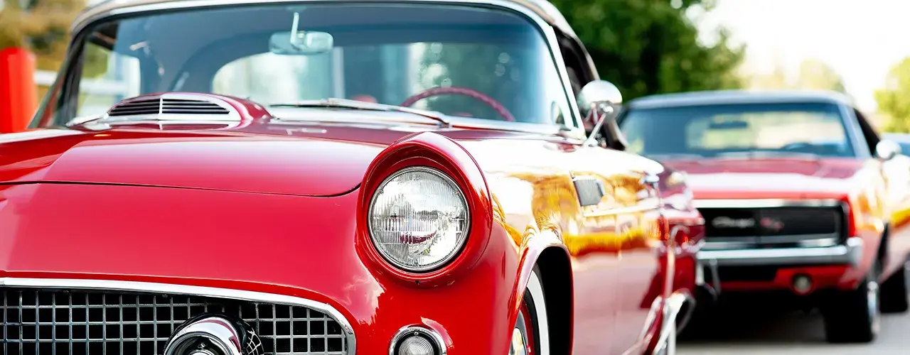 Several red classic cars lined up on a street.