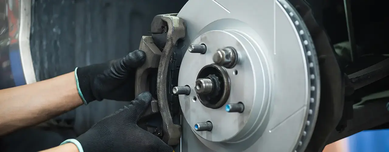 A person is inspecting and working on a car brake disc.