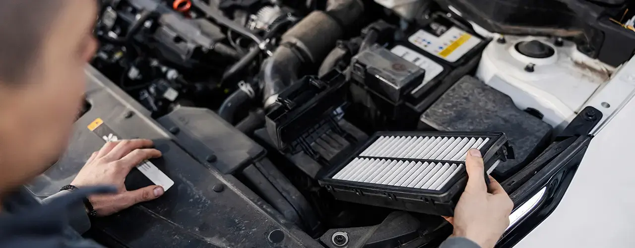 A man inspects the air filter in his car, demonstrating the process of changing car filters for maintenance.